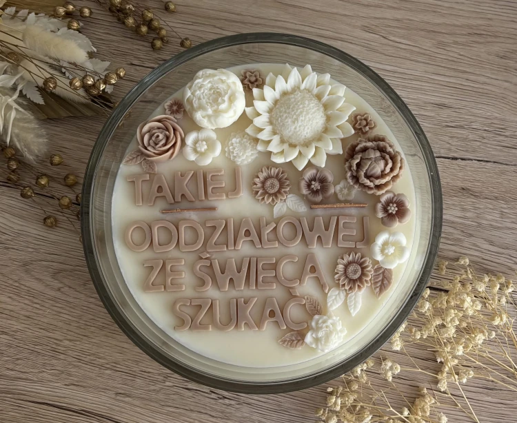 Świeca sojowa beżowo-kremowa z napisem.