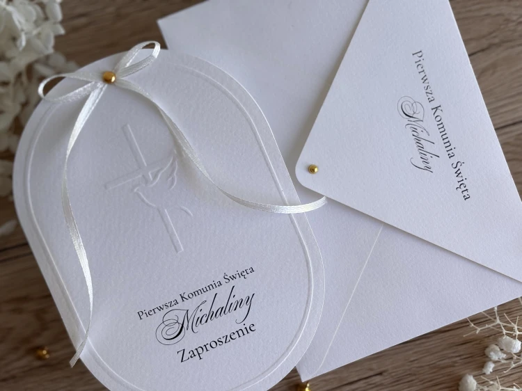 Zaproszenie na Komunię świętą na  fakturowanym papierze w klasycznym białym kolorze. Delikatne tłoczenie symbolu krzyża i gołębia.