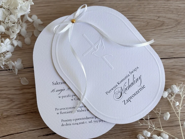 Eleganckie zaproszenie na Pierwszą Komunię Świętą z tłoczeniem krzyża i kielicha, białą wstążką i złotym detalem.
